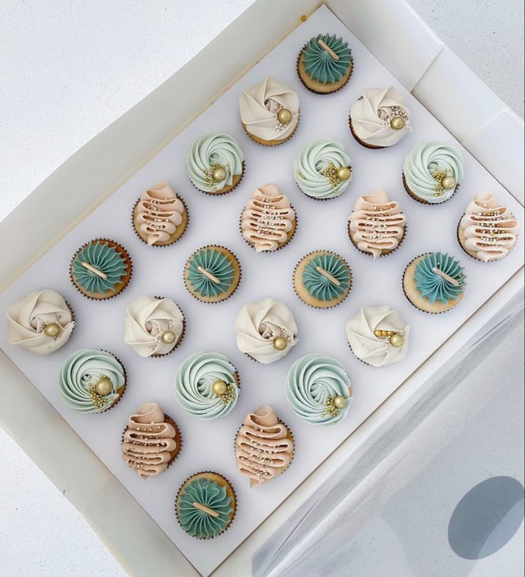 Assorted cupcakes in a box with various colors and designs.